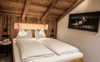 Rustikale Wandverkleidung aus handgehackten Altholzbrettern im Schlafzimmer